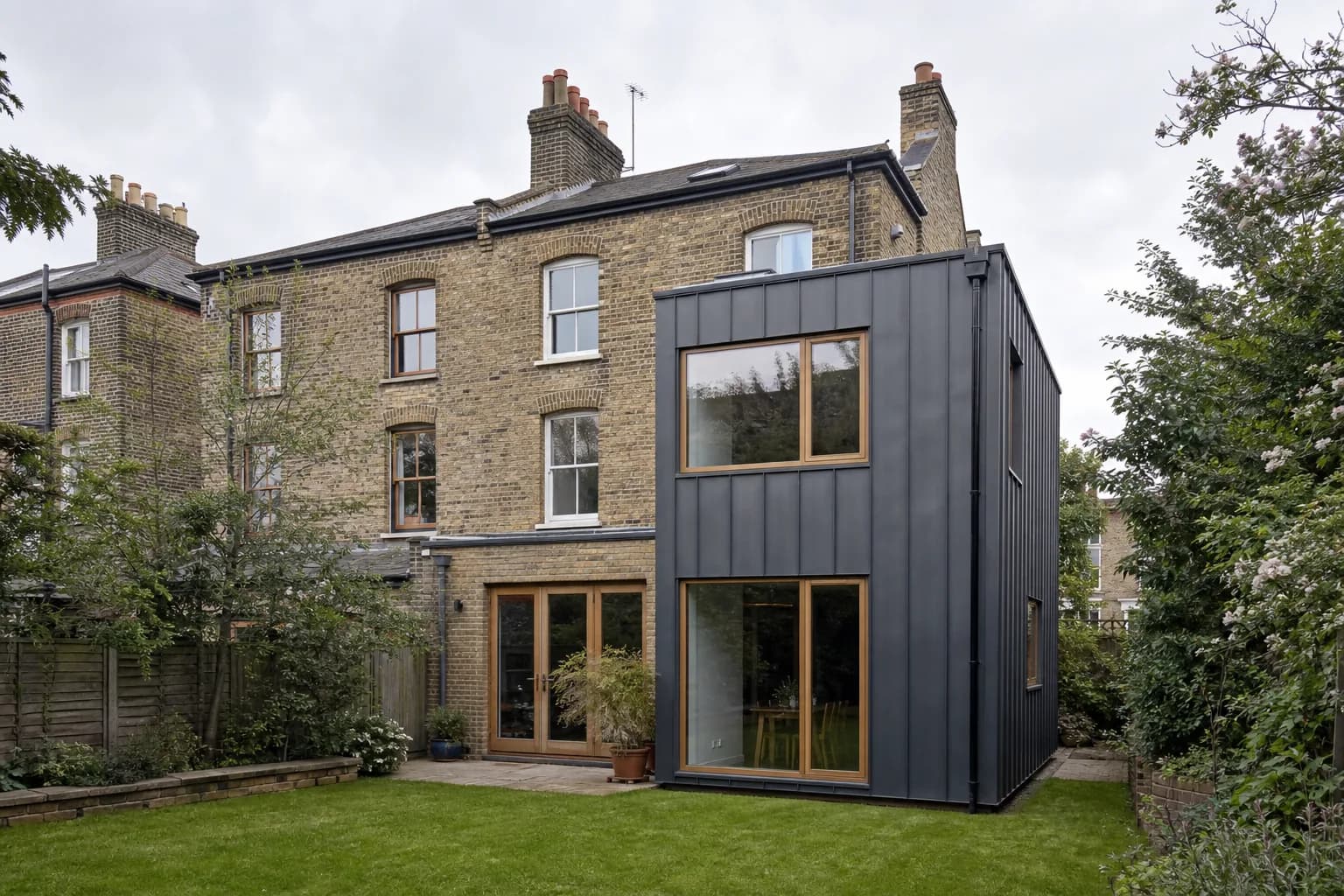 The rear of a Victorian semi-detached house with a new two-storey zinc-clad side extension